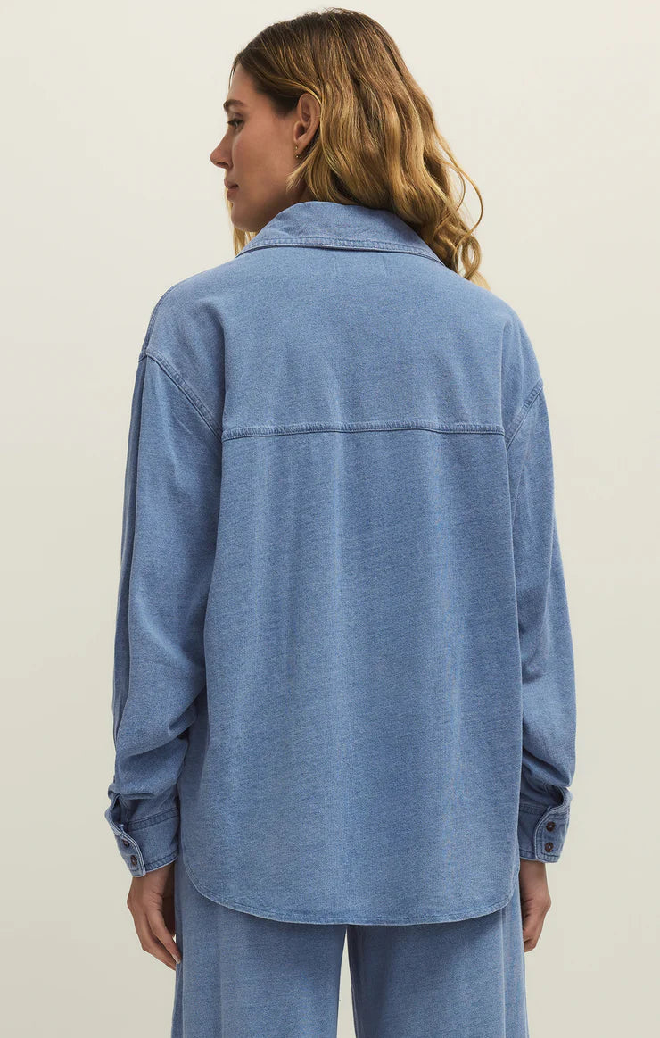 Woman wearing a blue denim shirt and pants on a plain background