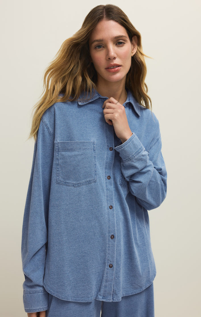 Woman wearing a blue denim shirt against a plain background