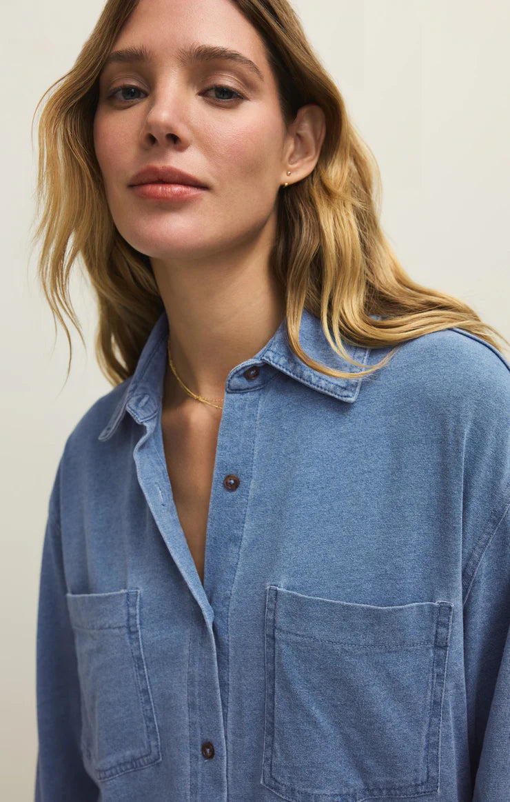 Woman wearing a blue denim shirt against a plain background