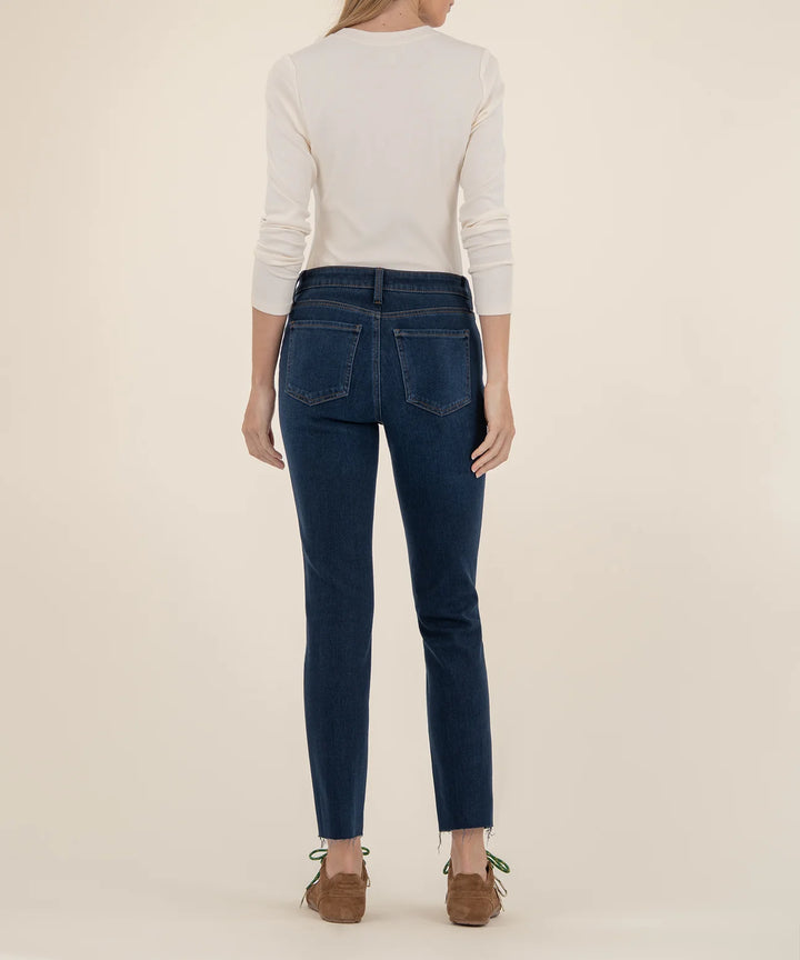 Person wearing blue jeans and a white sweater on a beige background