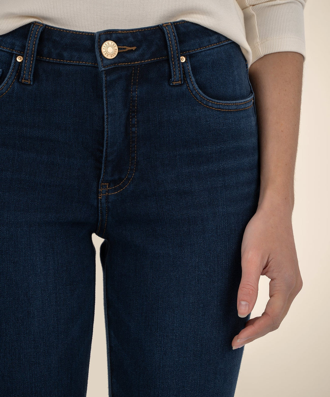 Close-up of dark blue jeans with a beige background