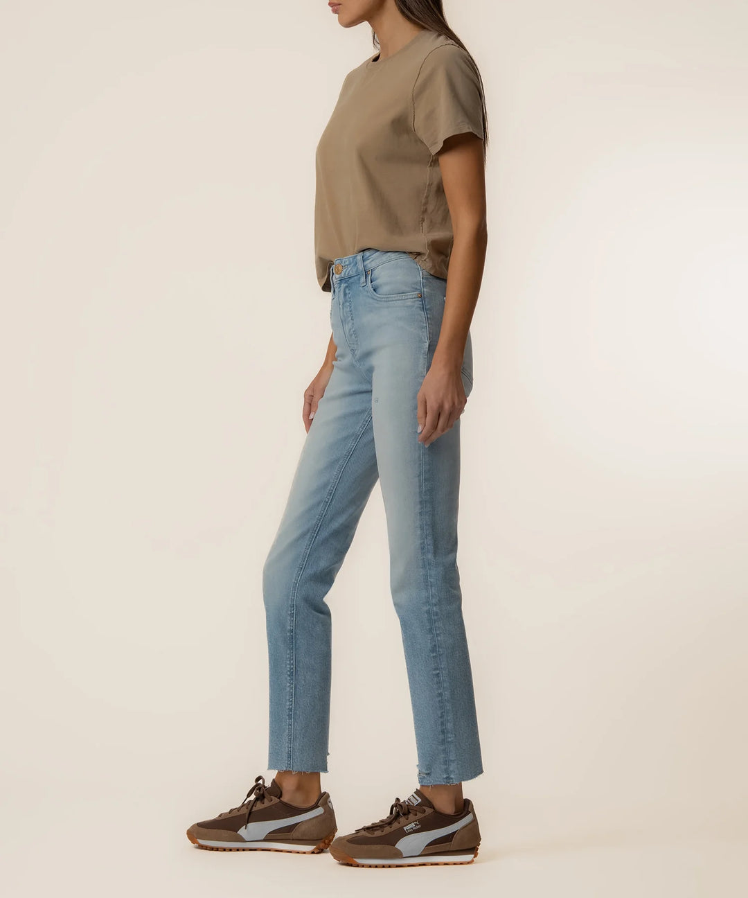 Person wearing a beige shirt and blue jeans on a plain background