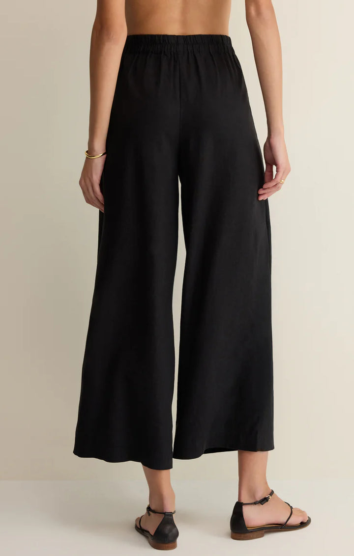 Person wearing black wide-leg pants on a beige background