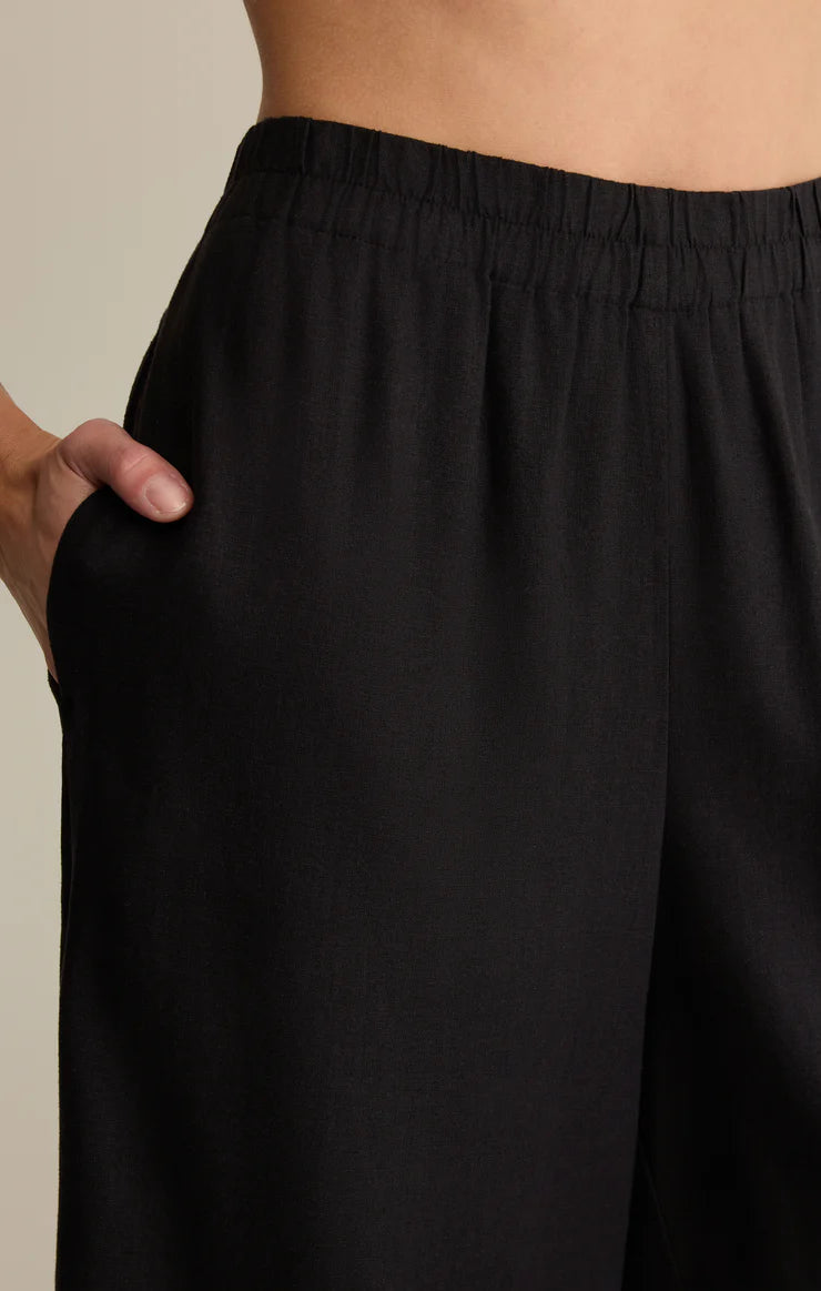 Black pants being worn against a neutral background
