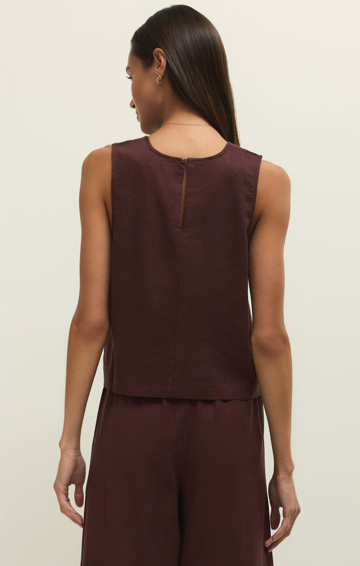 Woman wearing a brown sleeveless top and pants on a beige background