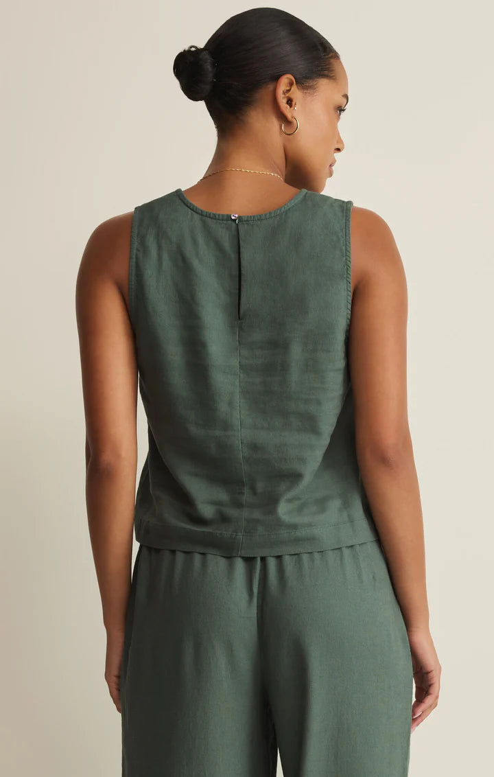 Woman wearing a green sleeveless top and pants set on a beige background