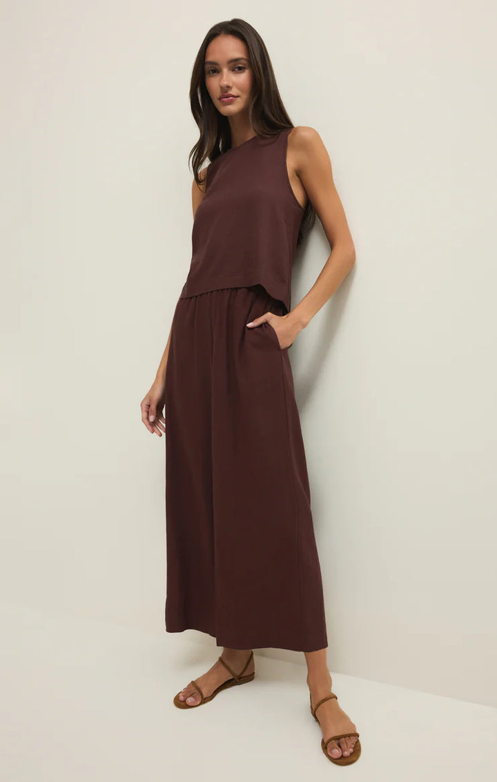 Woman wearing a brown sleeveless dress against a white background