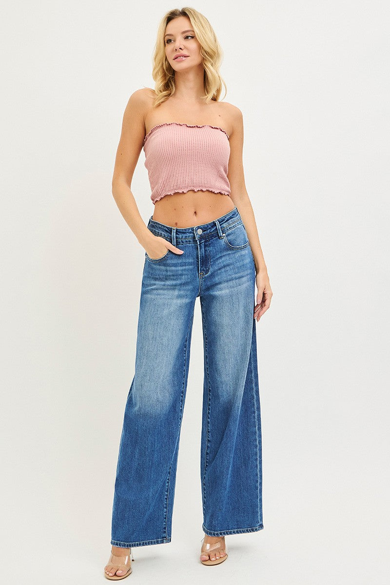 Woman wearing a pink strapless top and blue jeans on a white background
