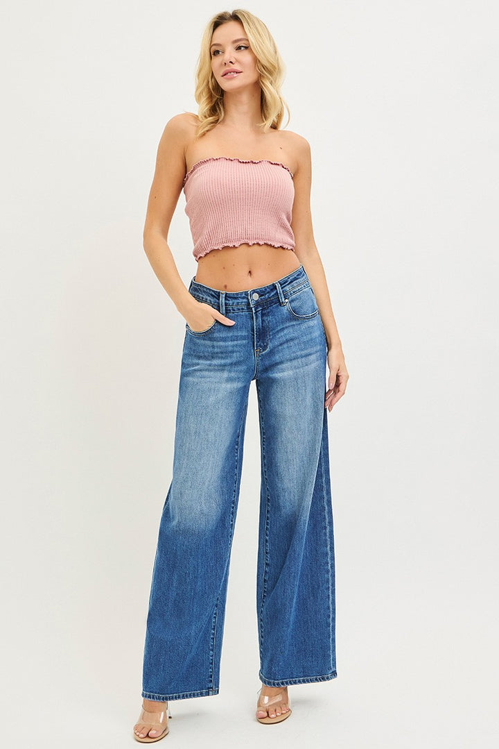 Woman wearing a pink strapless top and blue jeans on a white background