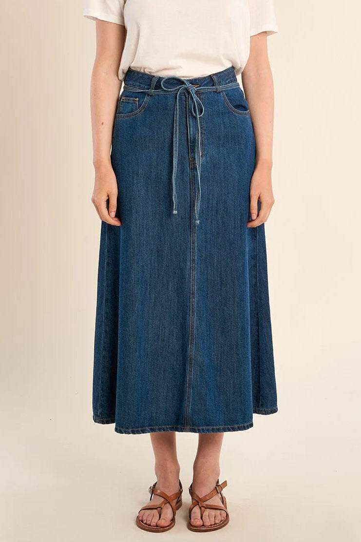 Person wearing a blue denim skirt on a beige background