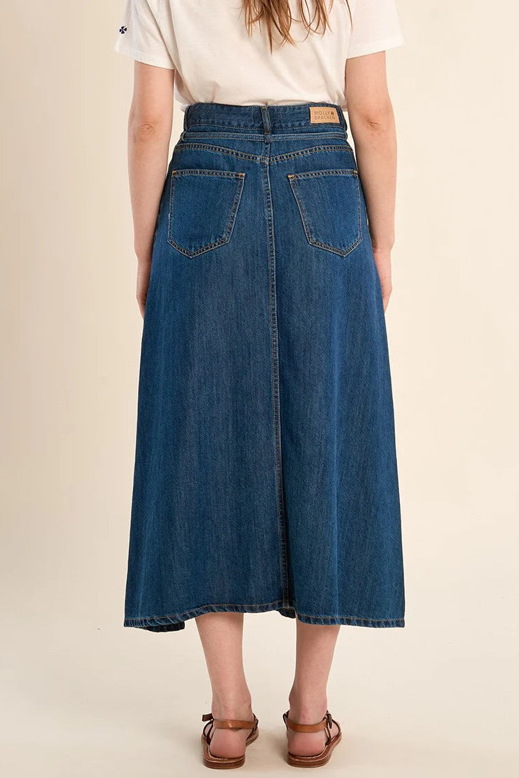 Person wearing a blue denim skirt on a beige background