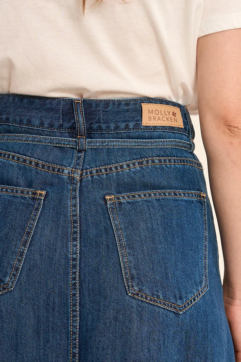 Close-up of blue jeans with a brand label on a neutral background