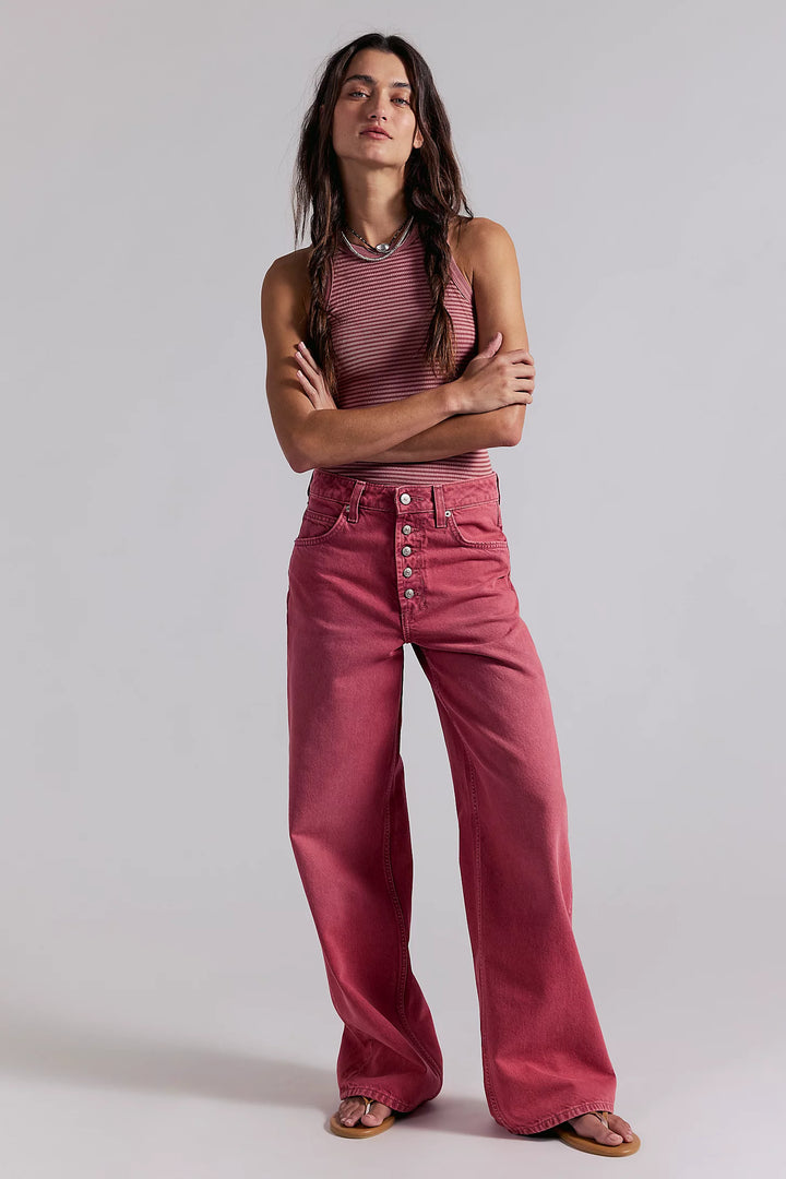 Woman wearing a pink outfit with wide-leg pants and a striped top on a plain background