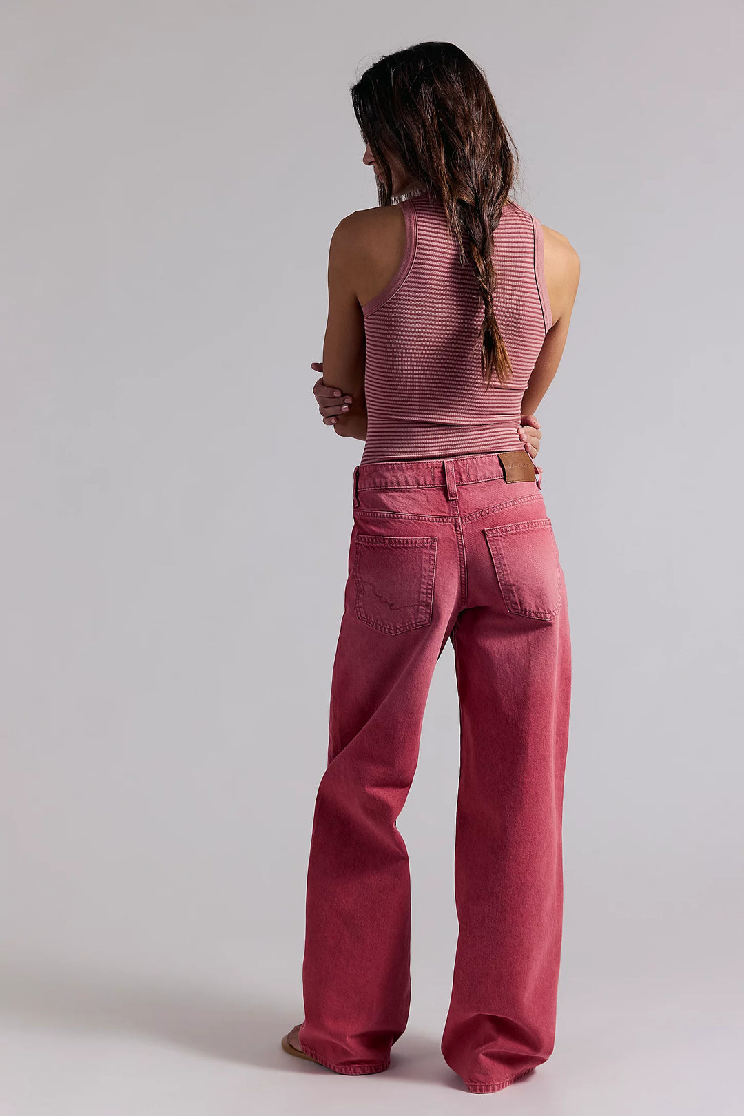 Person wearing a pink sleeveless top and pants on a plain background