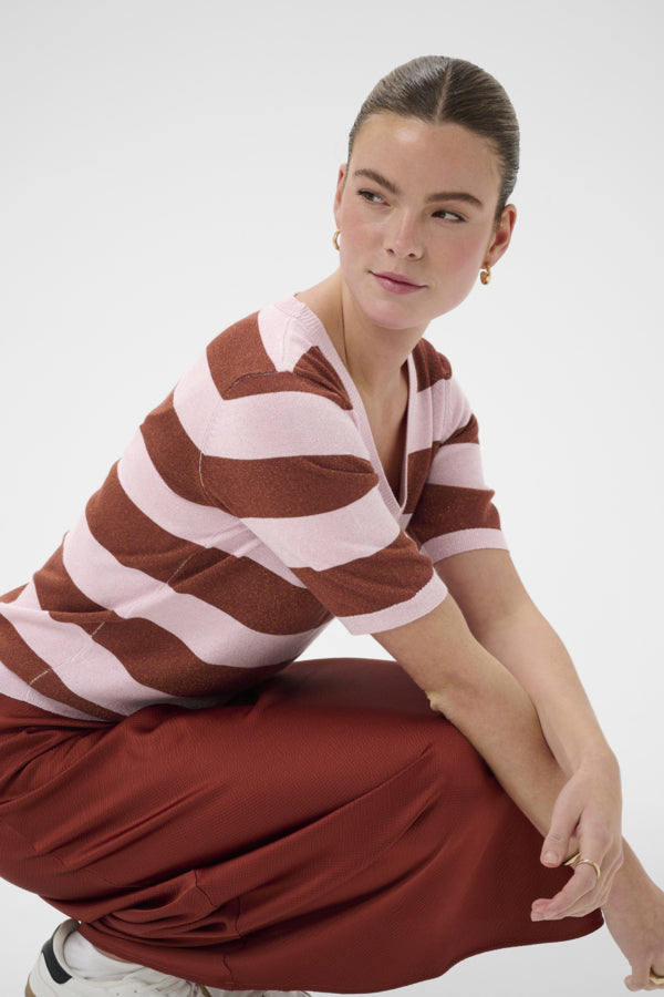 Woman wearing a brown and white striped shirt and red pants on a white background