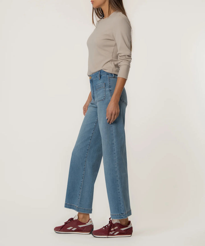 Person wearing blue jeans and a beige top on a white background