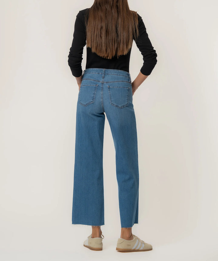 Person wearing blue jeans and a black top on a plain background