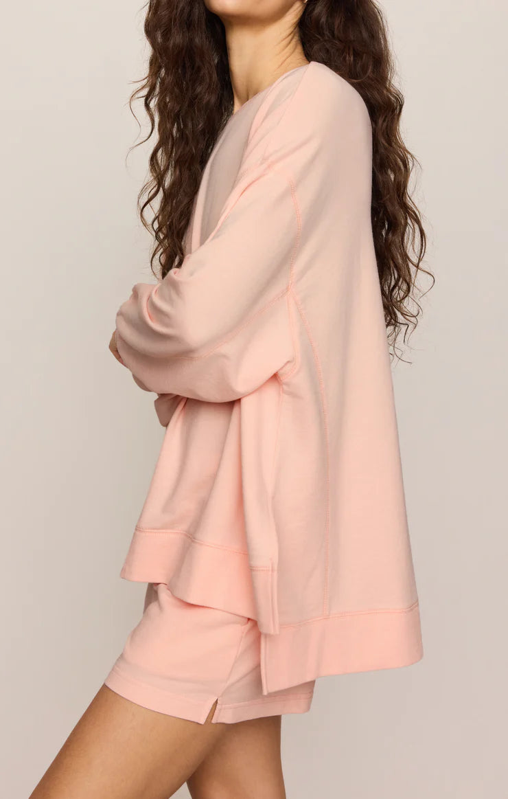 Woman wearing a light pink outfit with a matching cardigan on a plain background