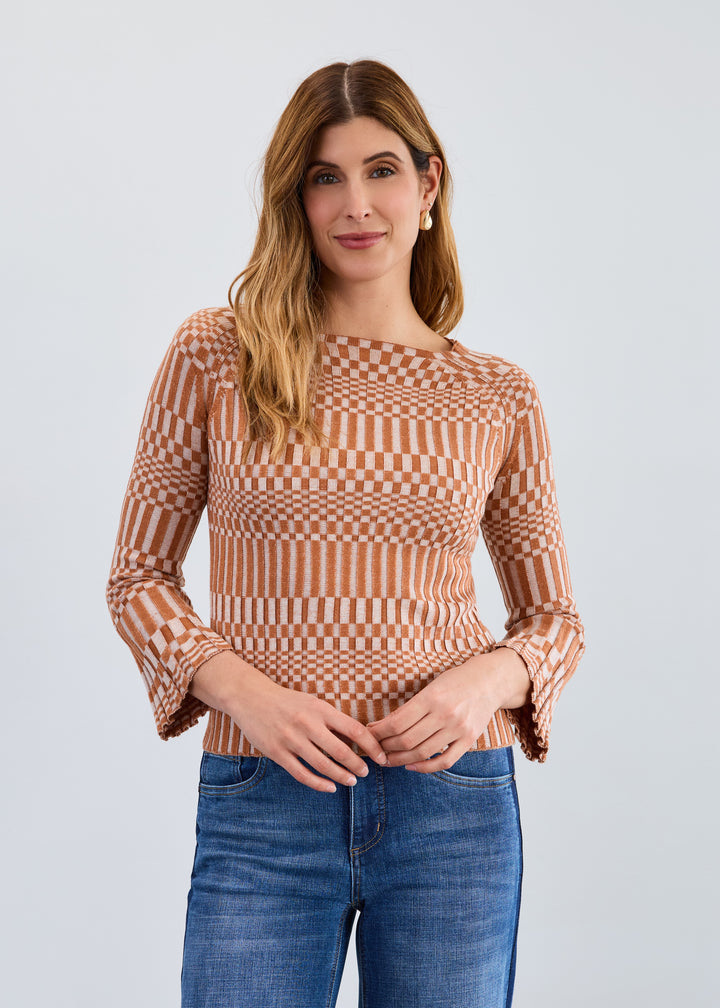 Woman wearing a patterned top and jeans against a plain background