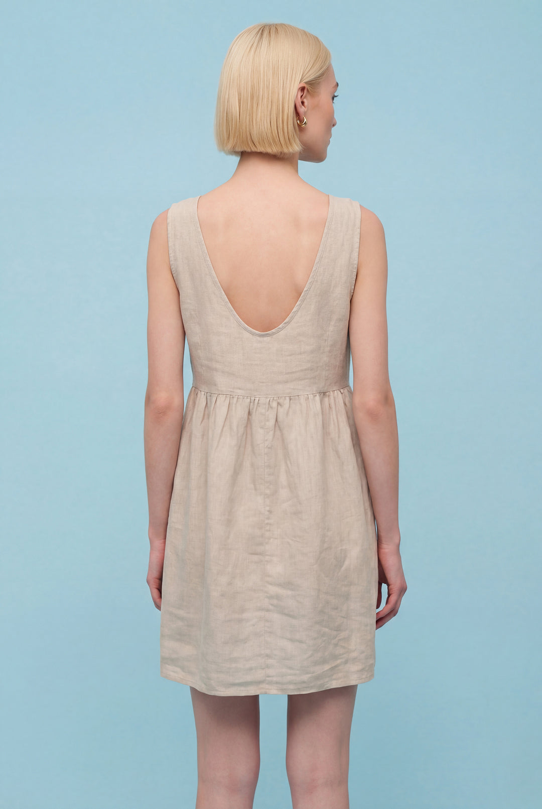 Woman wearing a beige dress against a light blue background