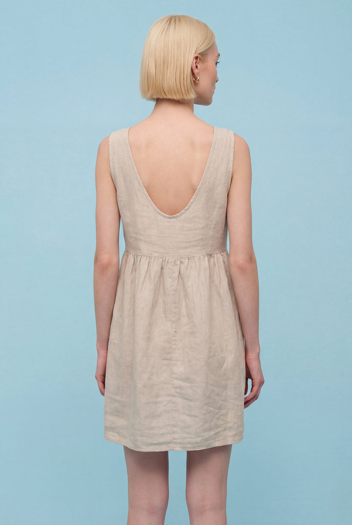 Woman wearing a beige dress against a light blue background