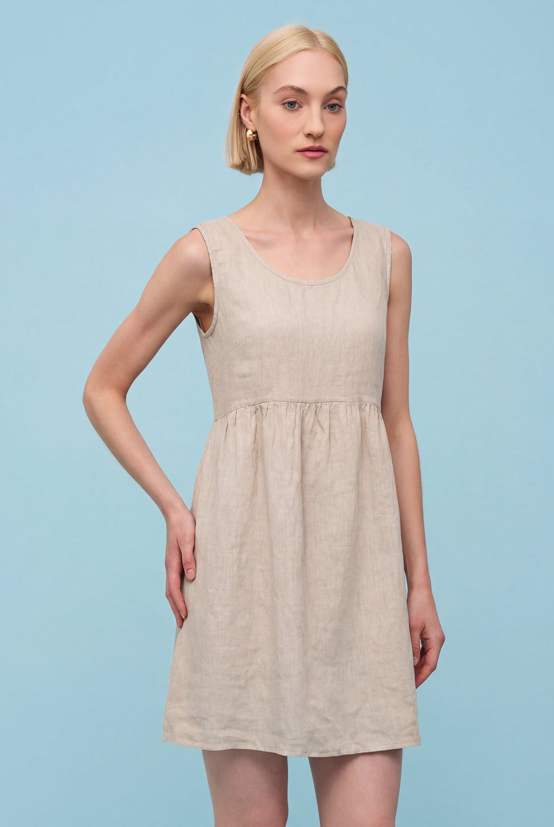 Woman wearing a beige dress against a light blue background