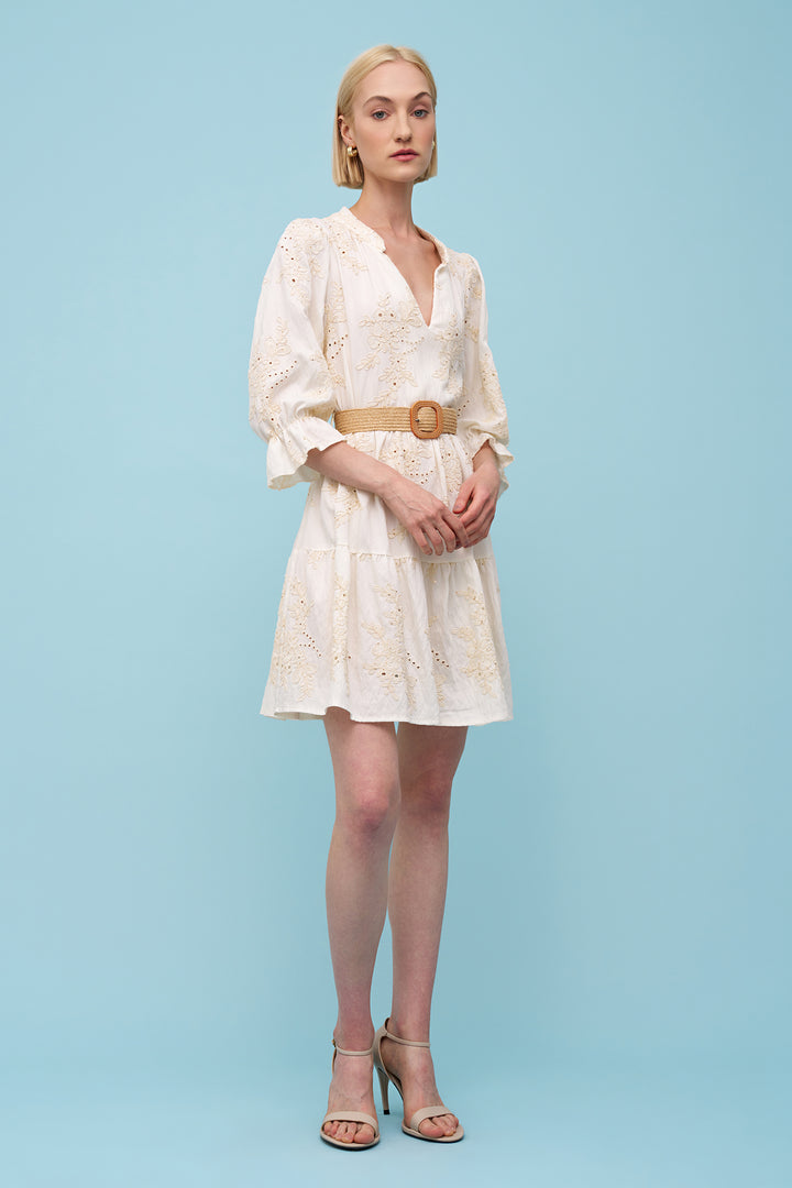 Woman wearing a white dress with a belt on a light blue background