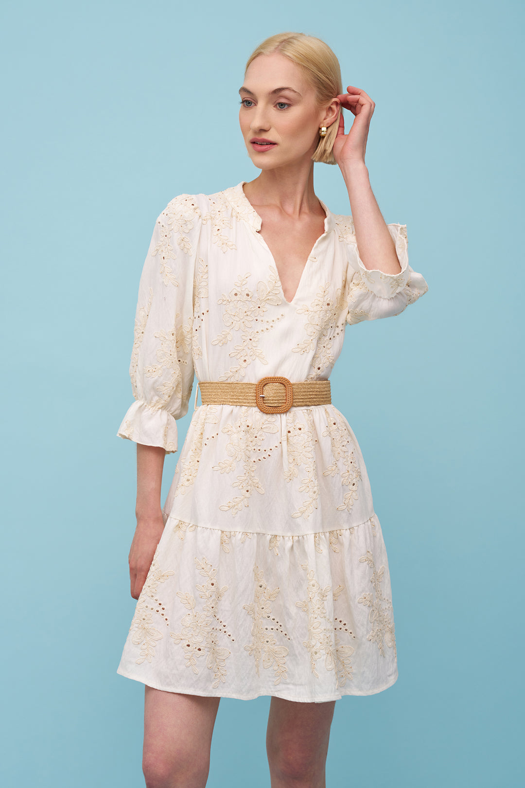 Woman wearing a white dress with a belt against a light blue background