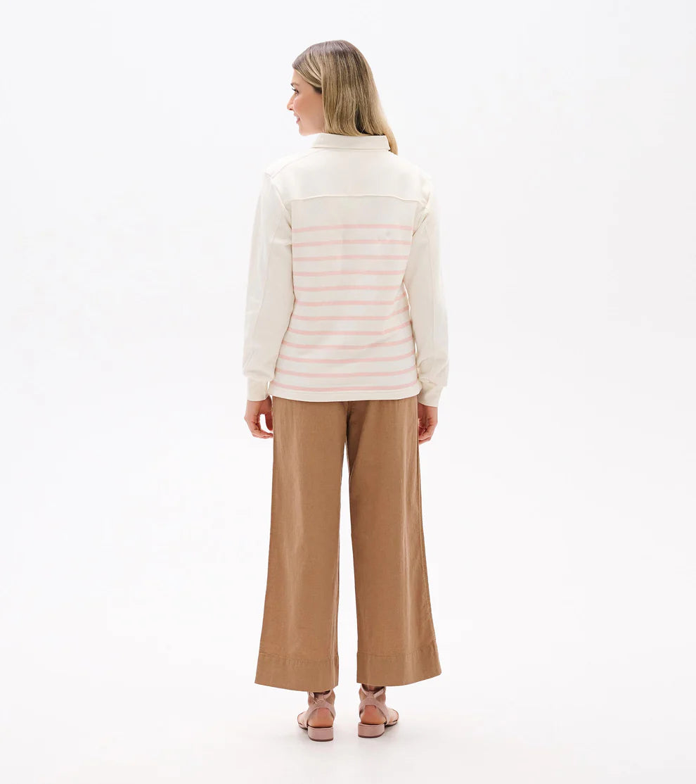Woman wearing a white puffer jacket and tan pants on a white background