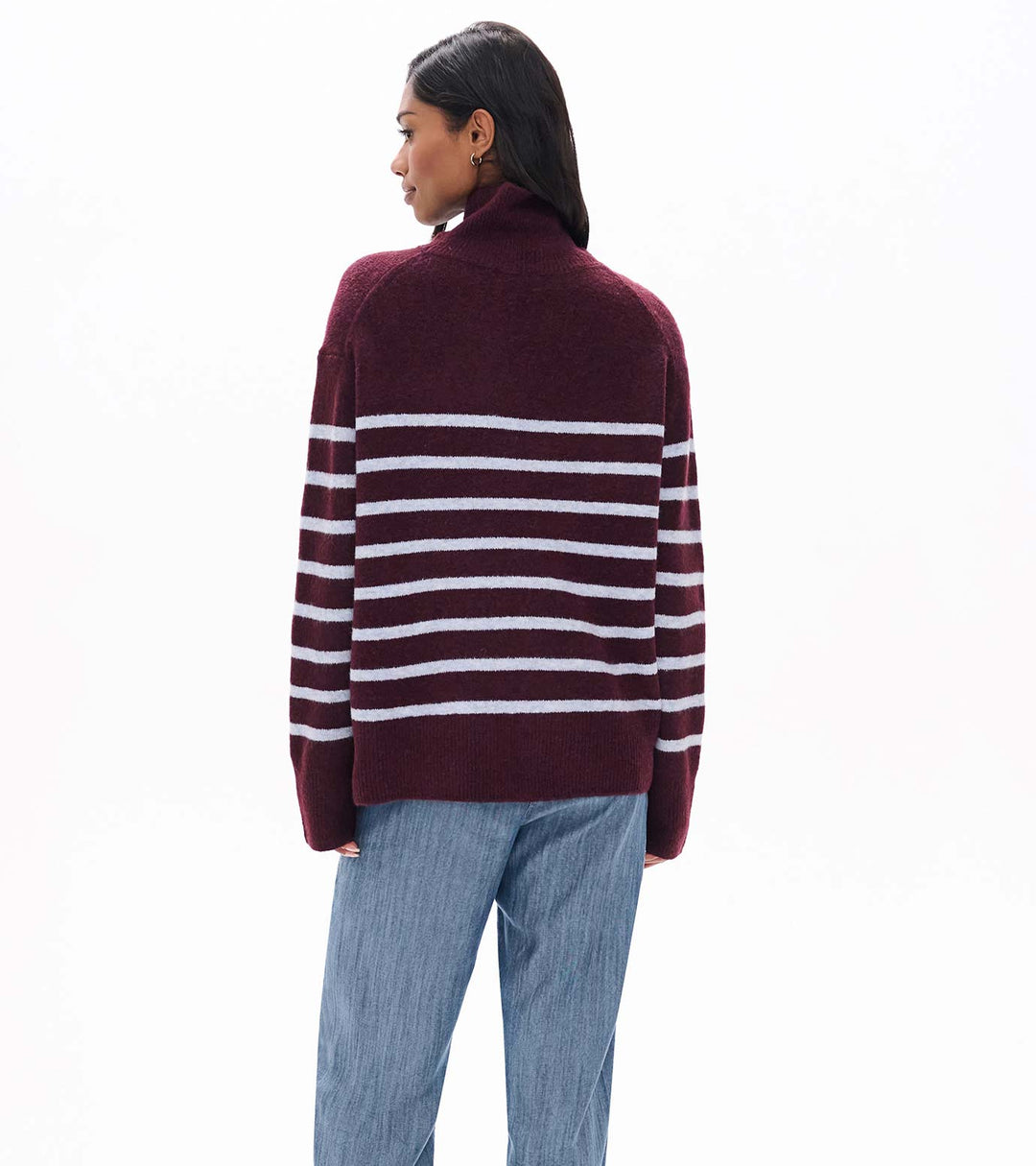Person wearing a maroon and white striped sweater with blue jeans on a white background