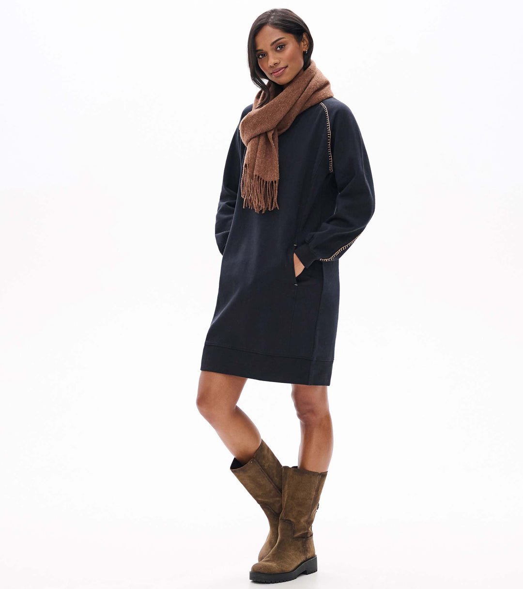 Woman wearing a navy dress, brown scarf, and brown boots on a white background