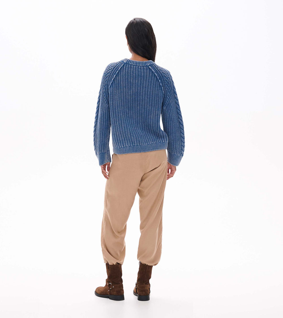 Person wearing a blue checkered sweater and beige pants on a white background