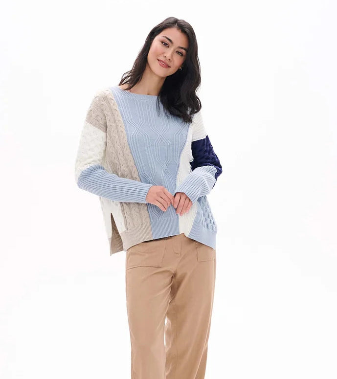 Woman wearing a colorful sweater and beige pants on a white background