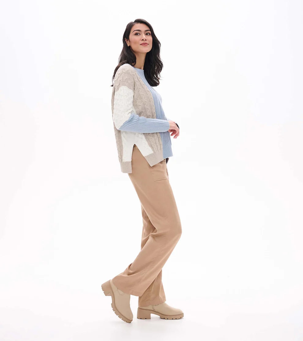 Woman wearing a patterned sweater and beige pants on a white background