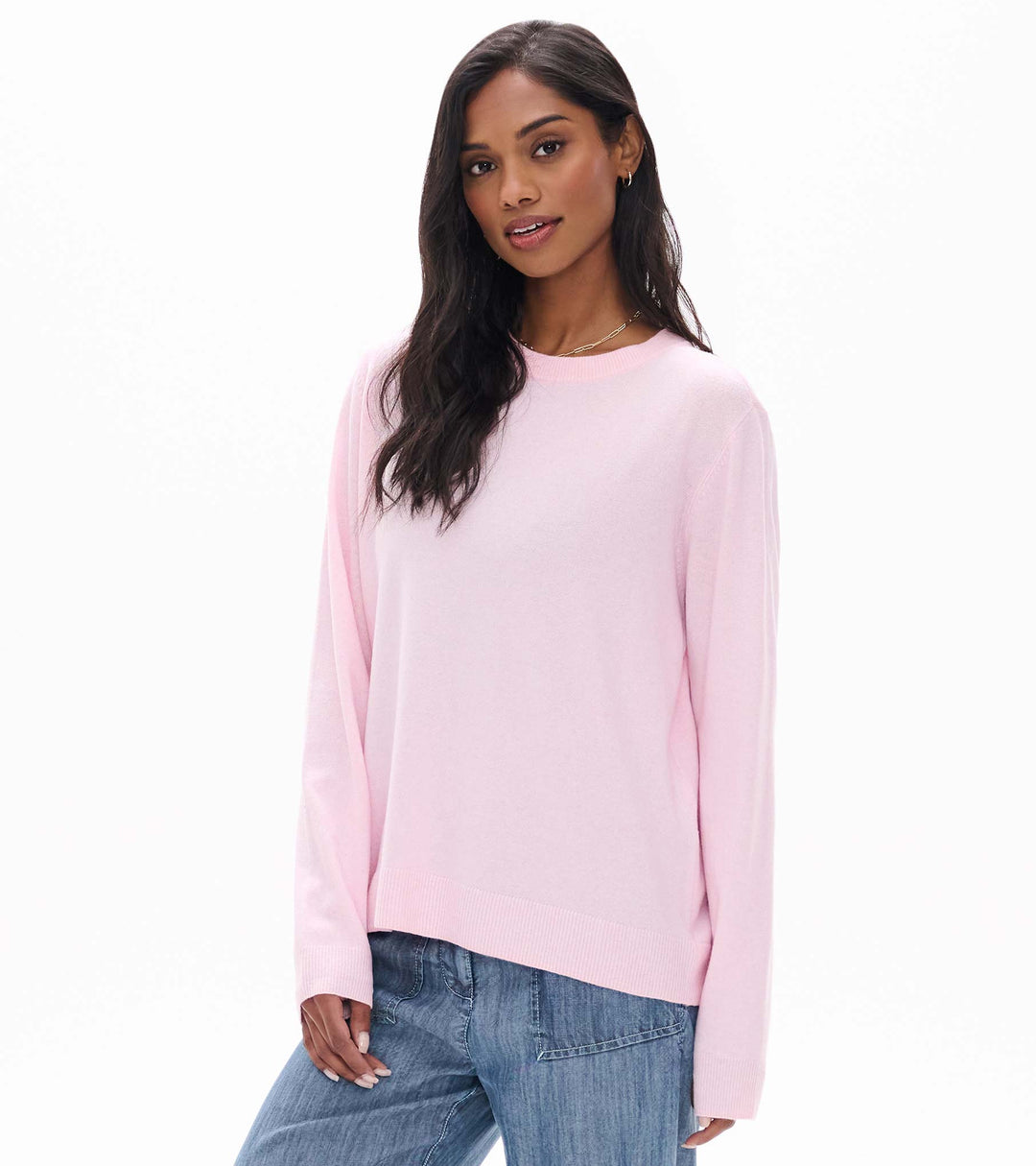 Woman wearing a pink sweater and blue jeans on a white background