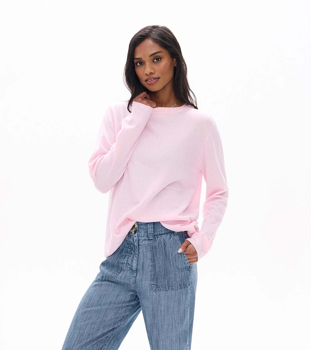 Woman wearing a pink sweater and blue jeans on a white background