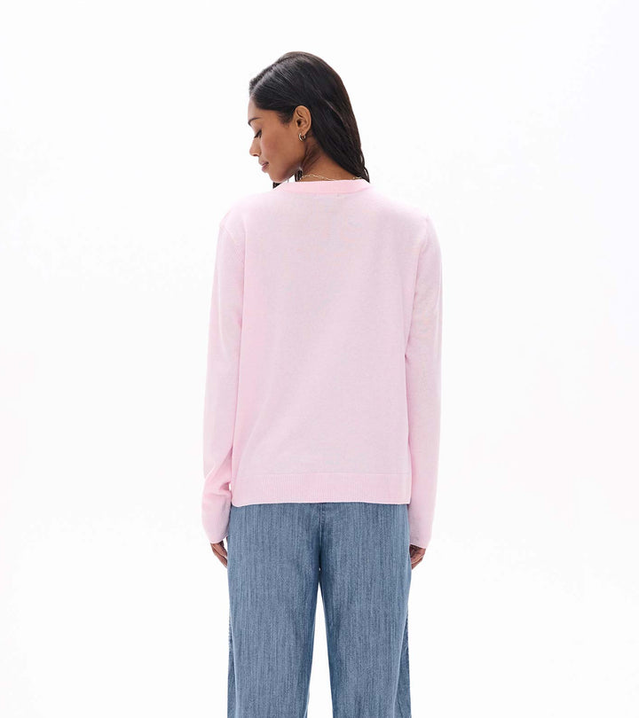Person wearing a light pink sweater and blue pants on a white background