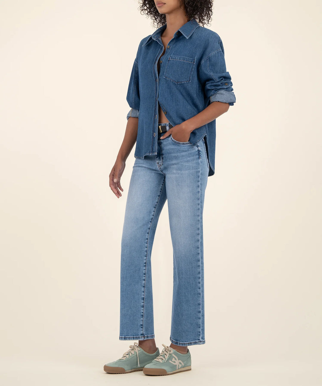 Person wearing a denim shirt and jeans on a beige background