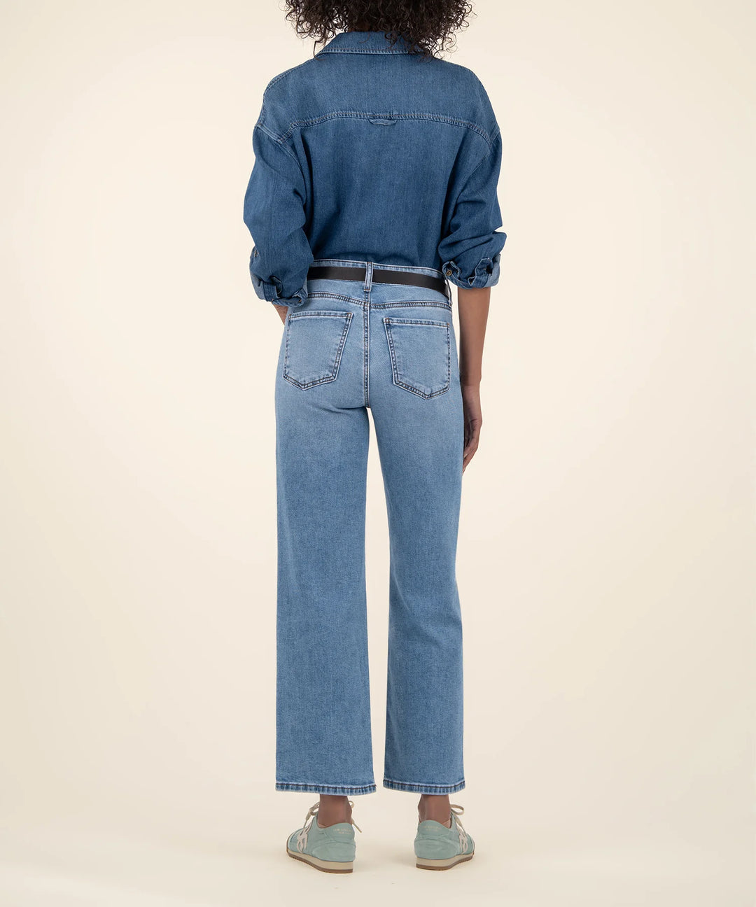 Person wearing a blue denim outfit on a beige background