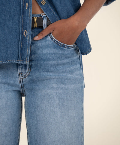 Close-up of a person wearing blue jeans with a beige background