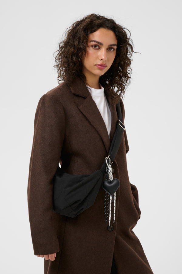 Woman wearing a brown coat with a black bag on a white background