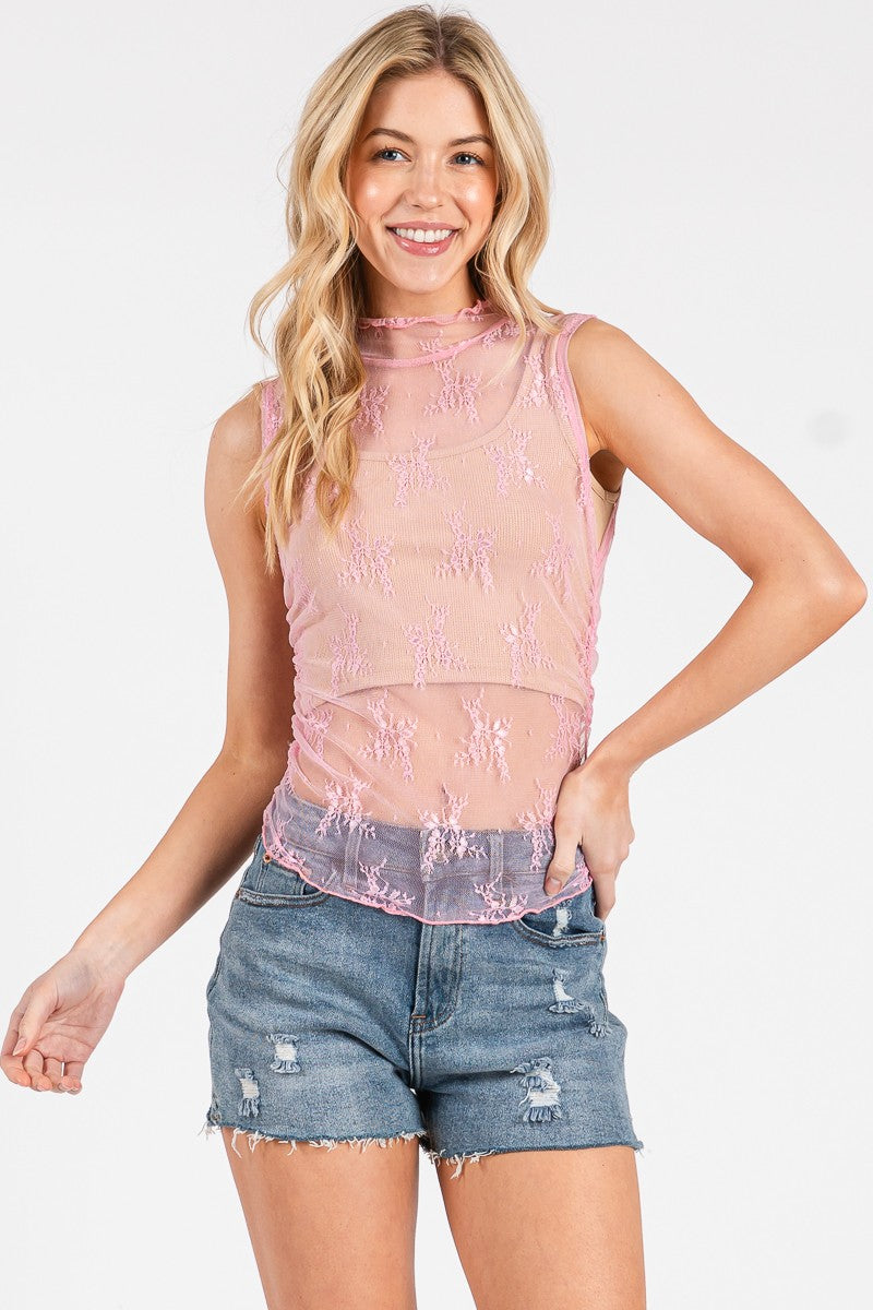 Woman wearing a pink lace top and denim shorts on a white background