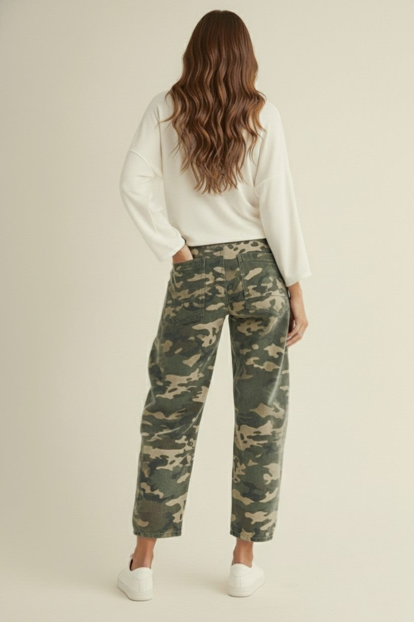 Woman wearing camouflage pants and a white top on a beige background