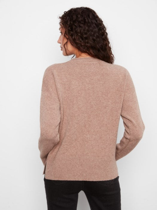 A woman shown from the back wearing a light dusty pink knit sweater and black pants against a plain white background.