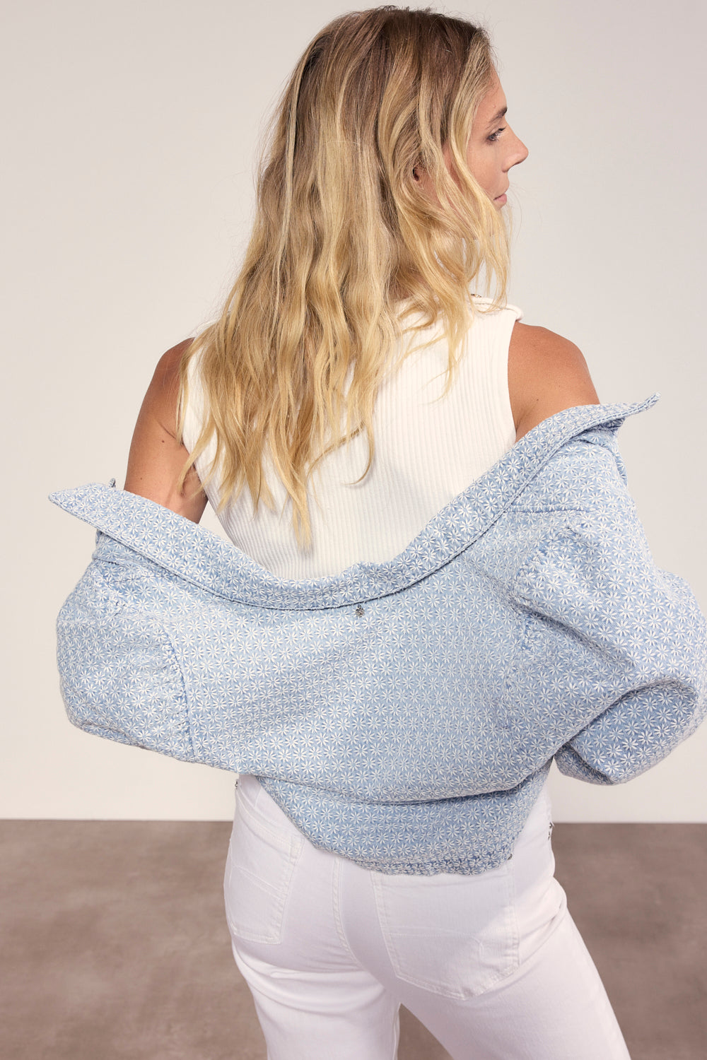 Woman wearing a light blue textured shawl over her shoulders against a plain background