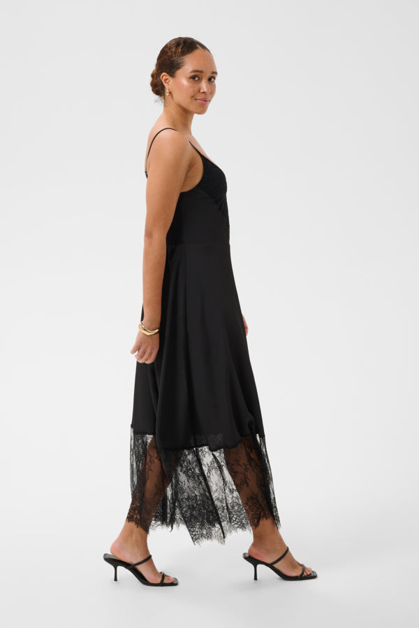 Woman wearing a black dress with lace overlay on a white background