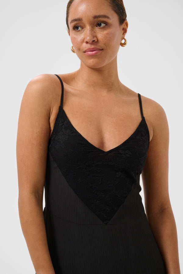 Woman wearing a black dress with thin straps against a white background