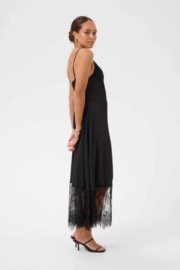 Woman wearing a black dress with lace detailing on a white background