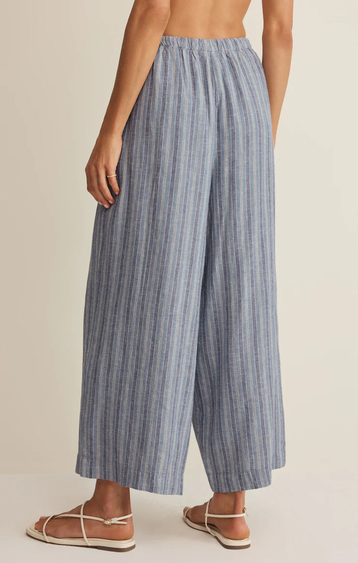 Blue striped wide-leg pants worn by a person on a beige background