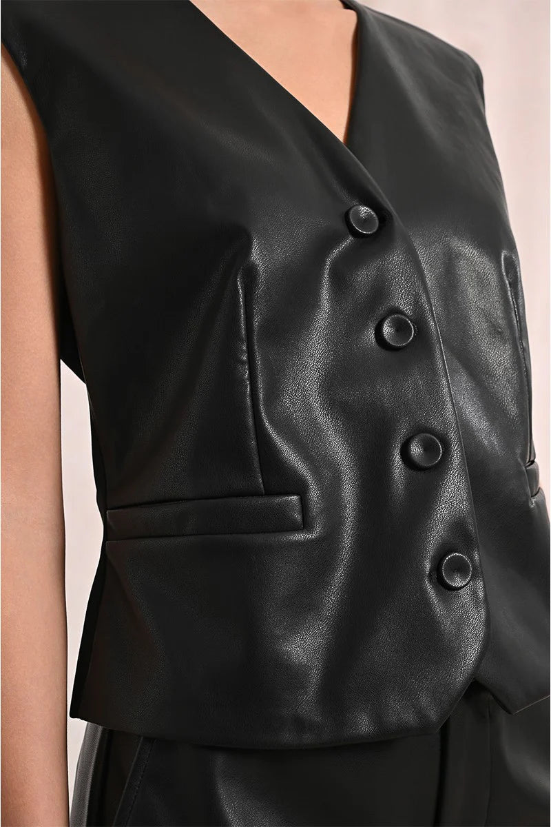 Black leather vest with buttons on a beige background